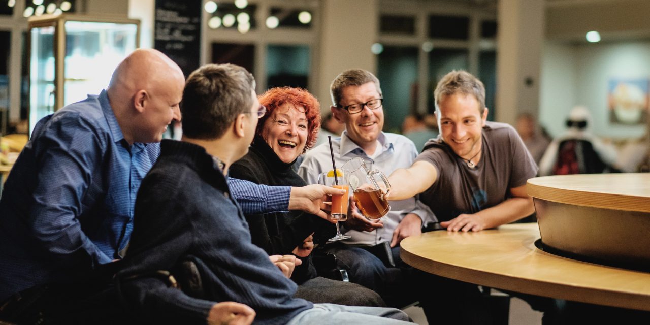 Menschen mit und ohne BEhinderung prosten sich zu.