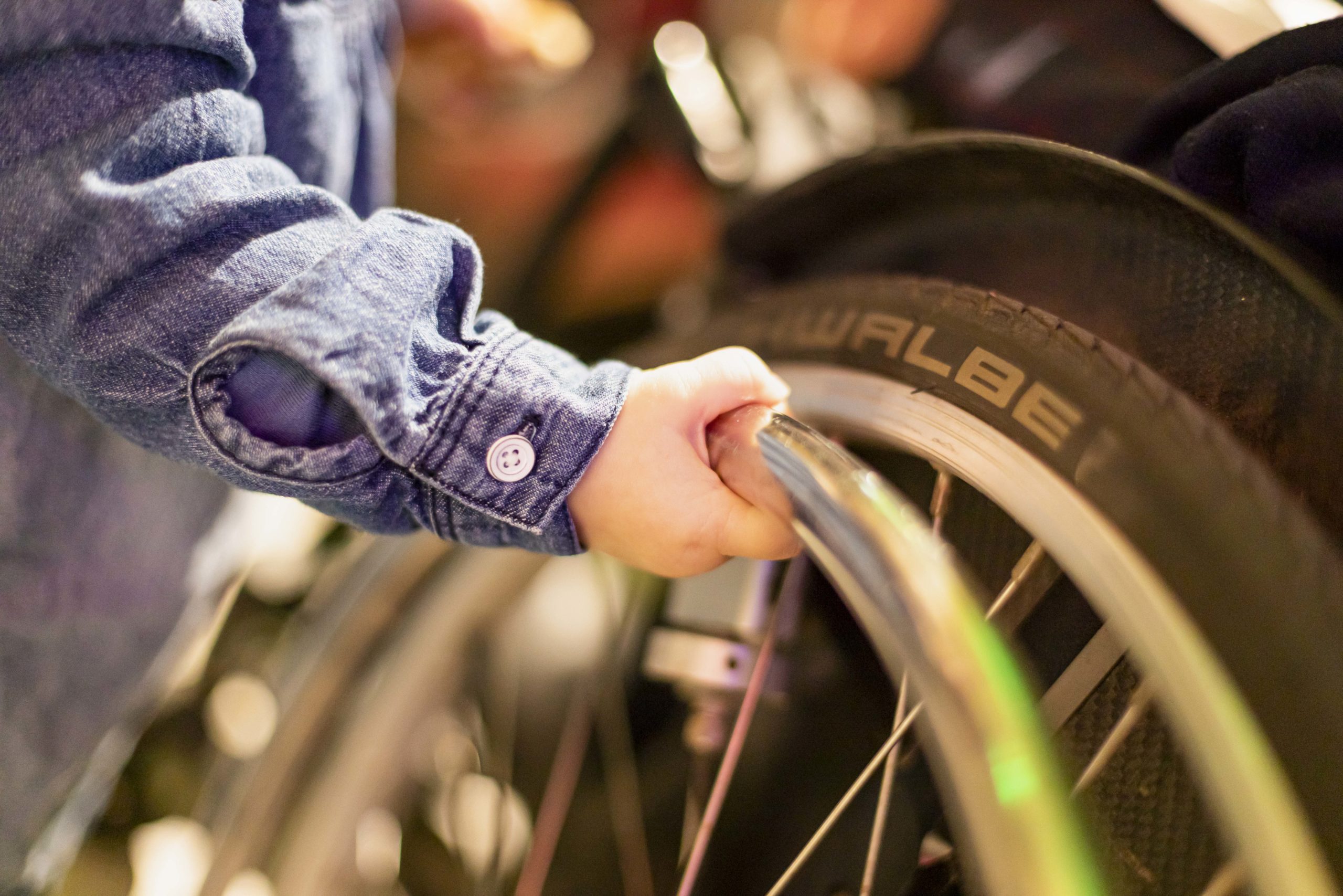 Eine Kinderhand greift an ein Rad eines Rollstuhls.