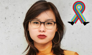 Eine asiatische Frau mit schwarzen schulterlangen Haaren schaut in die Kamera. Sie trägt eine Brille und einen gelben Pullover.