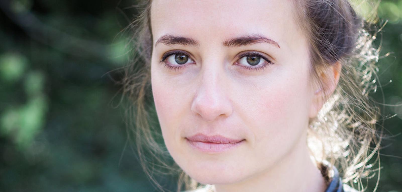 Das Gesicht einer weißen Frau mit grünen Augen und braunen Haaren schaut sanft in die Kamera. Es ist Anika Landsteiner.