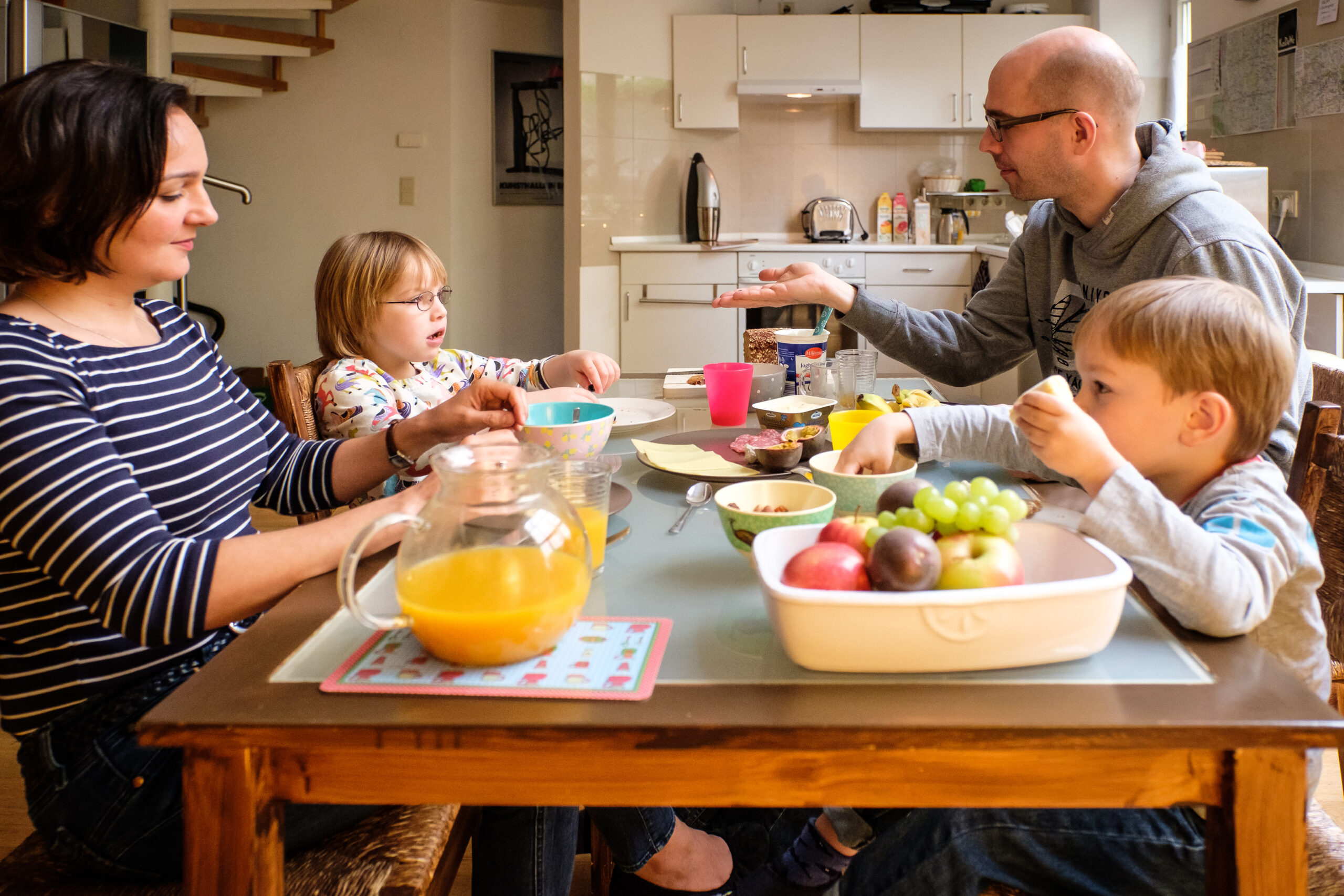 Eine weiße Familie sitzt gemeinsam am Tisch und isst Frühstück.