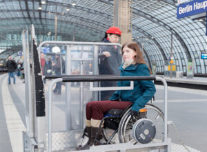 Eine Frau im Rollstuhl gelangt über eine Hebebühne in einen ICE