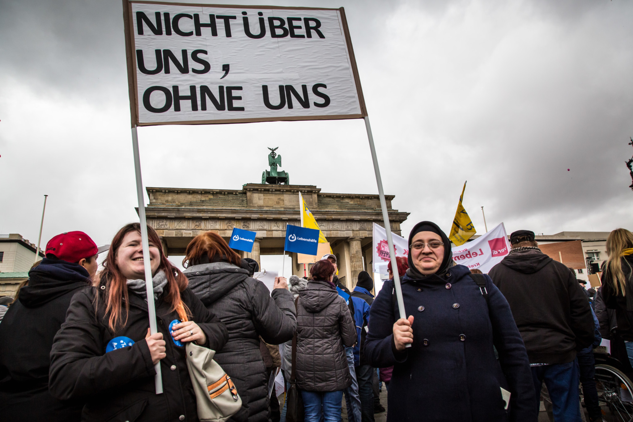 Auf einer Demonstration vor dem Brandenburger Tor halten zwei Personen ein Transparent mit der Aufschrift „nicht ohne und über uns“ hoch.