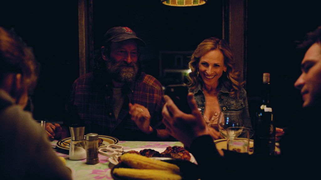 Ein ältererer Mann und eine Frau am Esstisch. Sie unterhalten sich und lachen dabei.