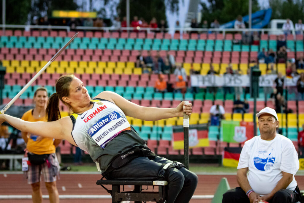 Eine Sportlerin sitzt im Rollstuhl und wirft einen Speer.