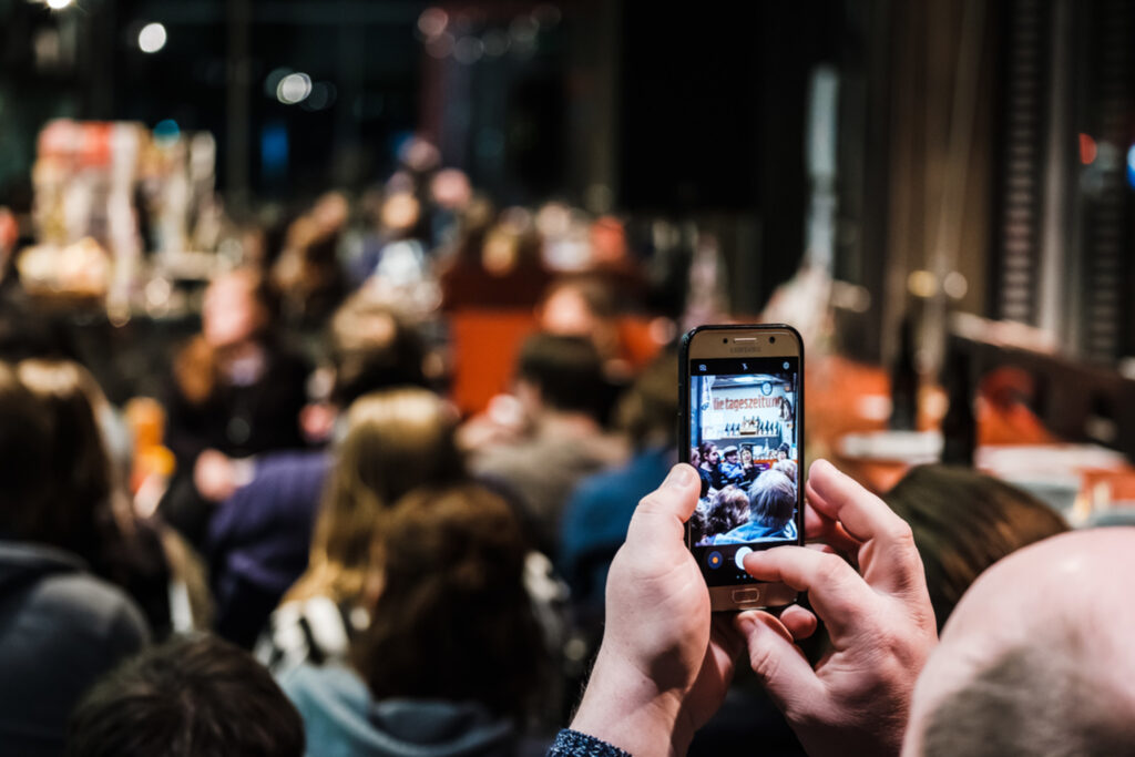Bei einer Veranstaltung hält eine Person ihr Smartphone hoch und macht ein Foto.