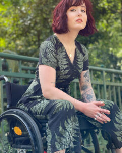 Die Aktivistin und Autorin Luisa L’Audace sitzt im Rollstuhl und blickt in die Kamera.