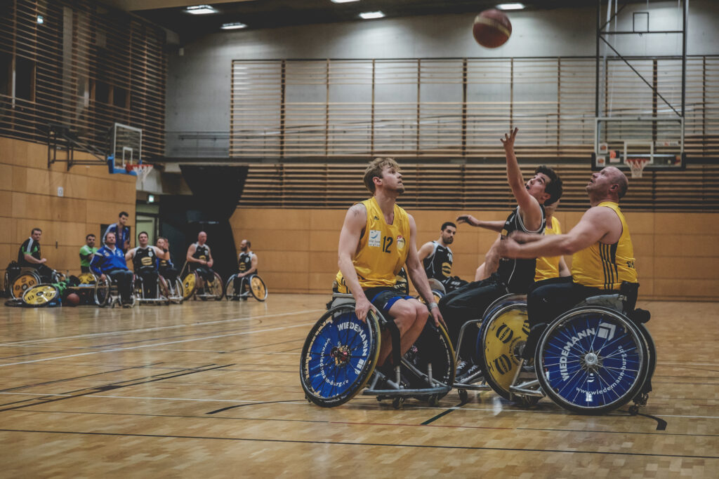 Foto von einem von einem Rollstuhlbasketball-Spiel der Alba Berlin Rollis gegen Baskets 96 Rahden. Beide Teams kämpfen um den Ball.