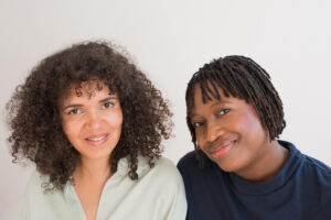 Doppelportrait der beiden Autorinnen Tebogo Nimindé-Dundadengar und Olaolu Fajembola, beide lächeln in die Kamera.