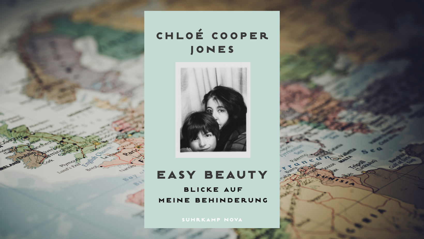 Das Buchcover „Easy Beauty. Blicke auf meine Behinderung“ der Autorin Chloé Cooper Jones ist vor einer leicht verschwommenen Weltkarte zu sehen, die Teile Europas und Nordafrikas anschneiden. Das Buchcover zeigt ein Foto von Jones und ihrem Sohn in Schwarzweiß vor einem hellbauen Hintergrund.