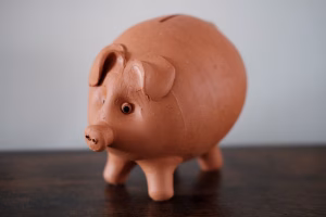 Selbstgetöpfertes, rosa Sparschwein auf einem braunen Tisch.
