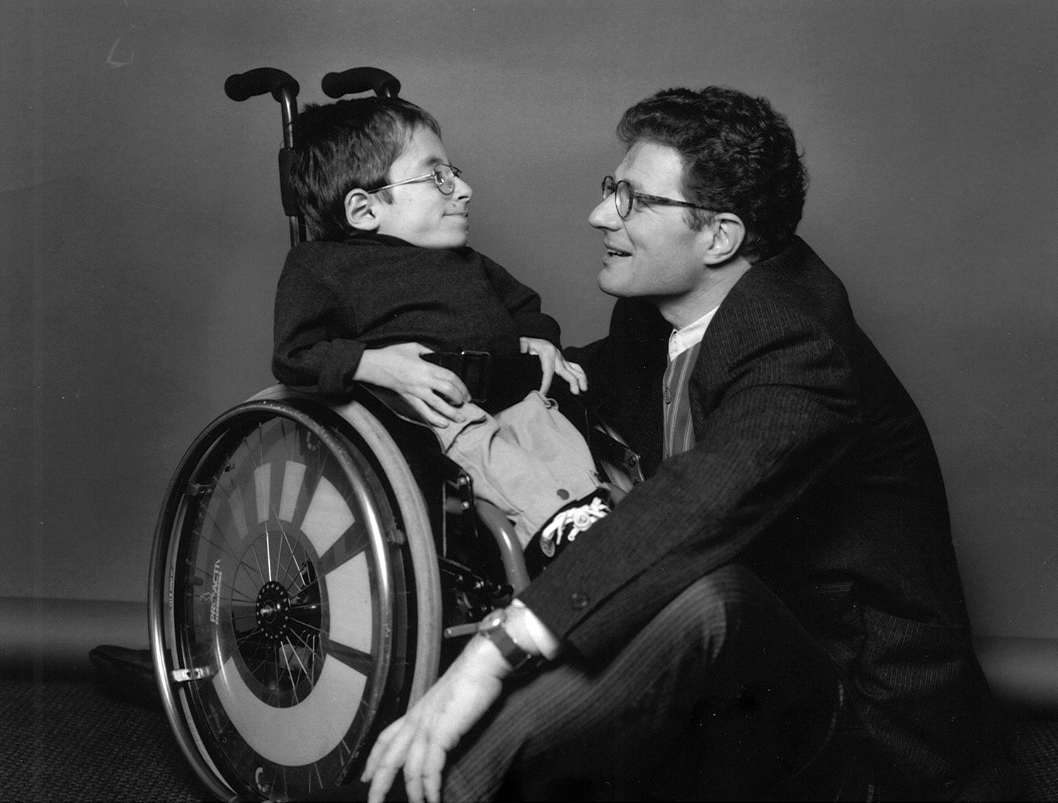 Schwarz-Weiß bild von dem jungen Raul Krauhausen. vor ihm kniet Roger Willemsen. Beide schauen sich in die Augen.